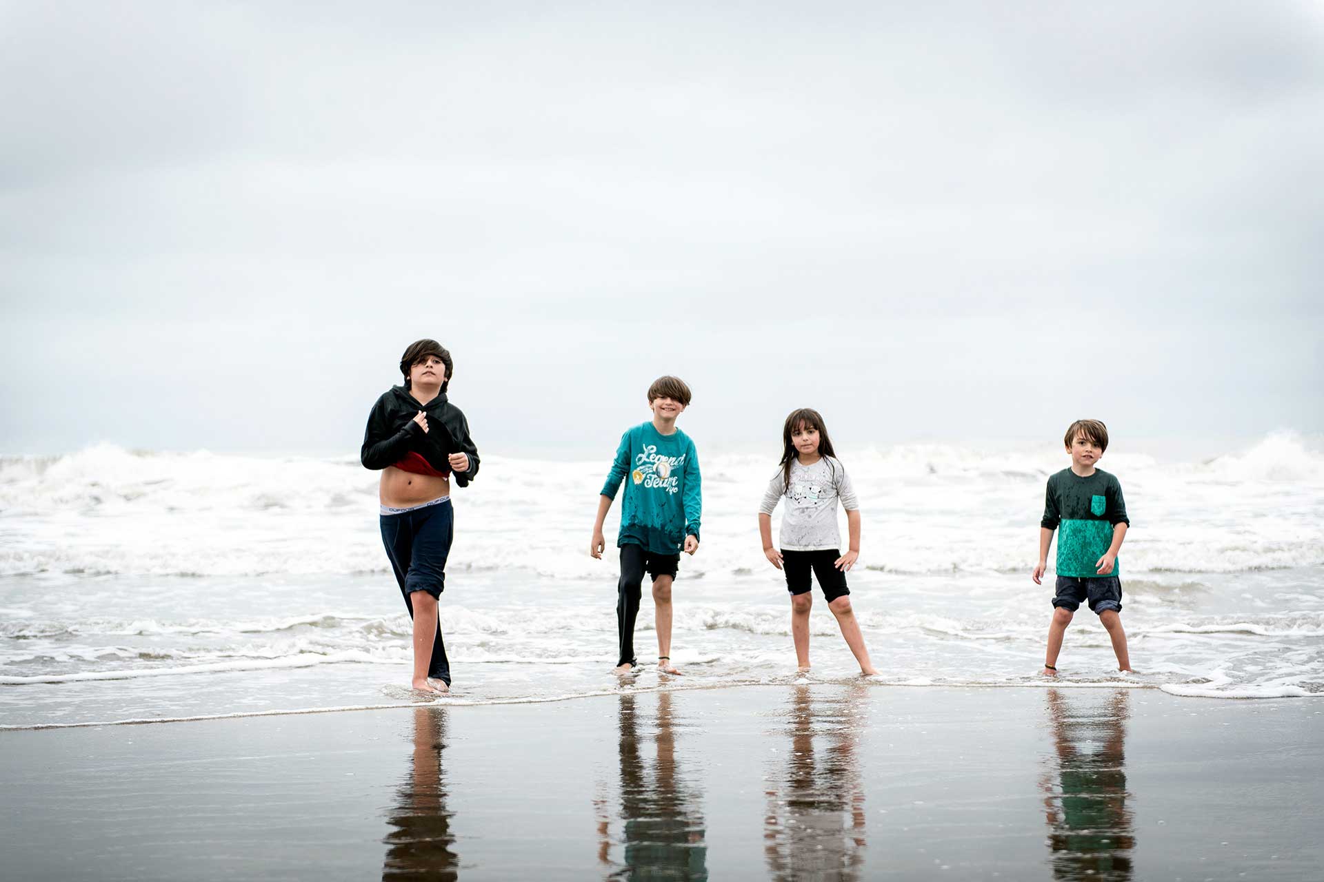 Primos. Fotografía de 4 primos con sus ropas mojadas, jugando a la orilla del mar