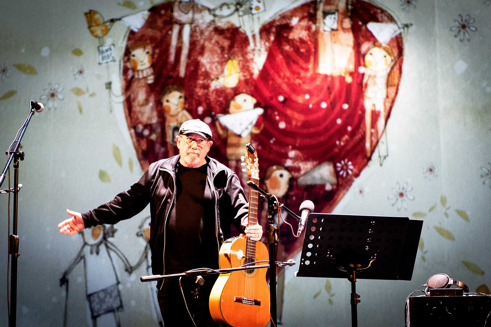 Fotografía de Silvio Rodríguez de pie y con su guitarra en mano saludando y agradeciendo al público