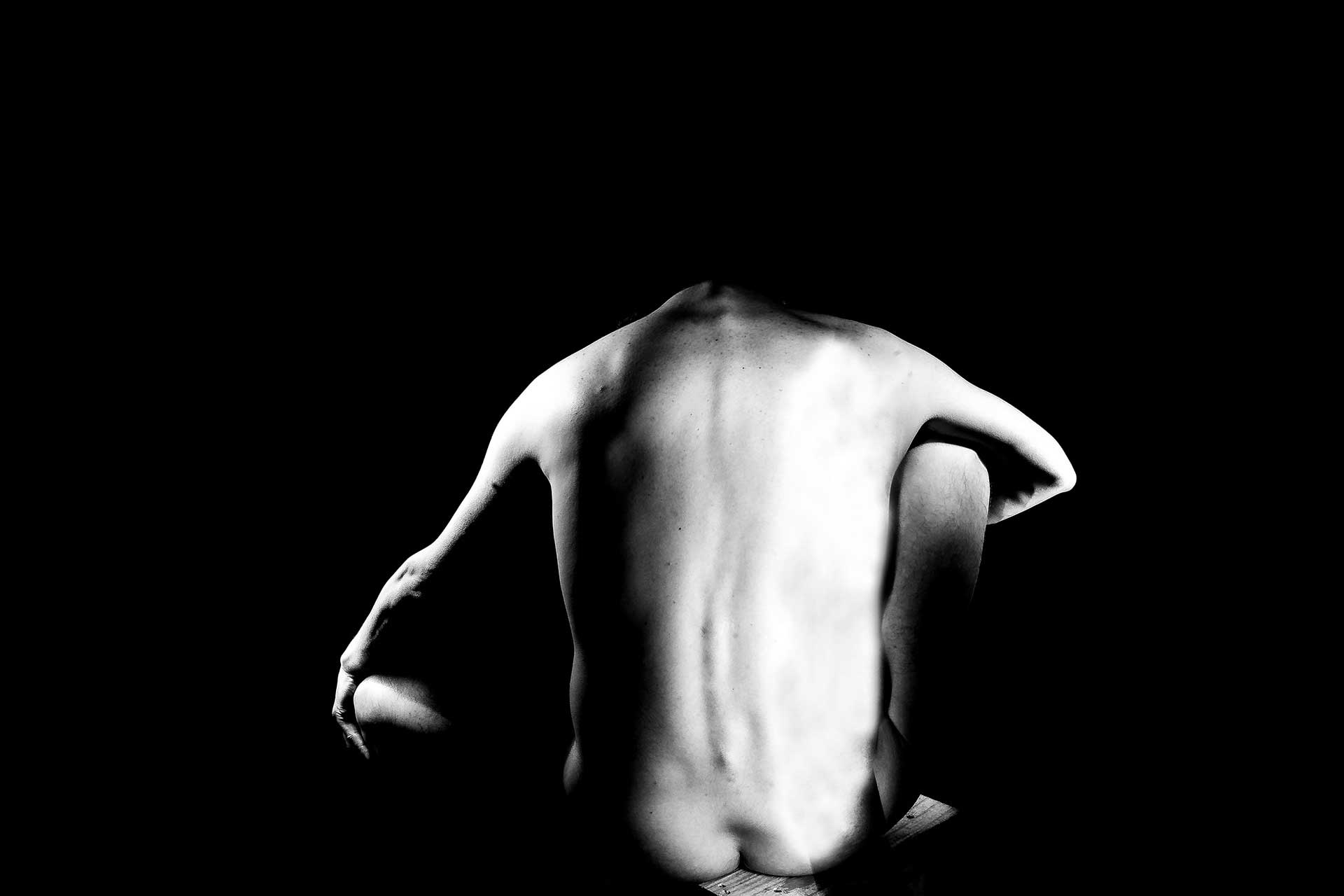 Fotografía, en blanco y negro, de un cuerpo iluminado en la oscuridad
